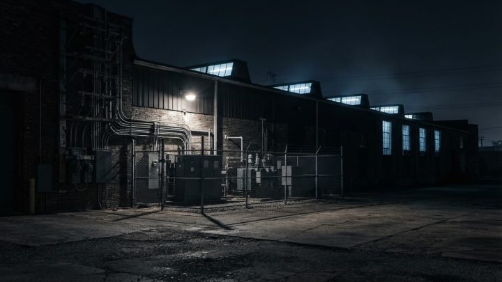 Imagen ilustrativa: exterior nocturno de una planta industrial en operación, con su acometida eléctrica y el patio de equipo enrejado al frente.